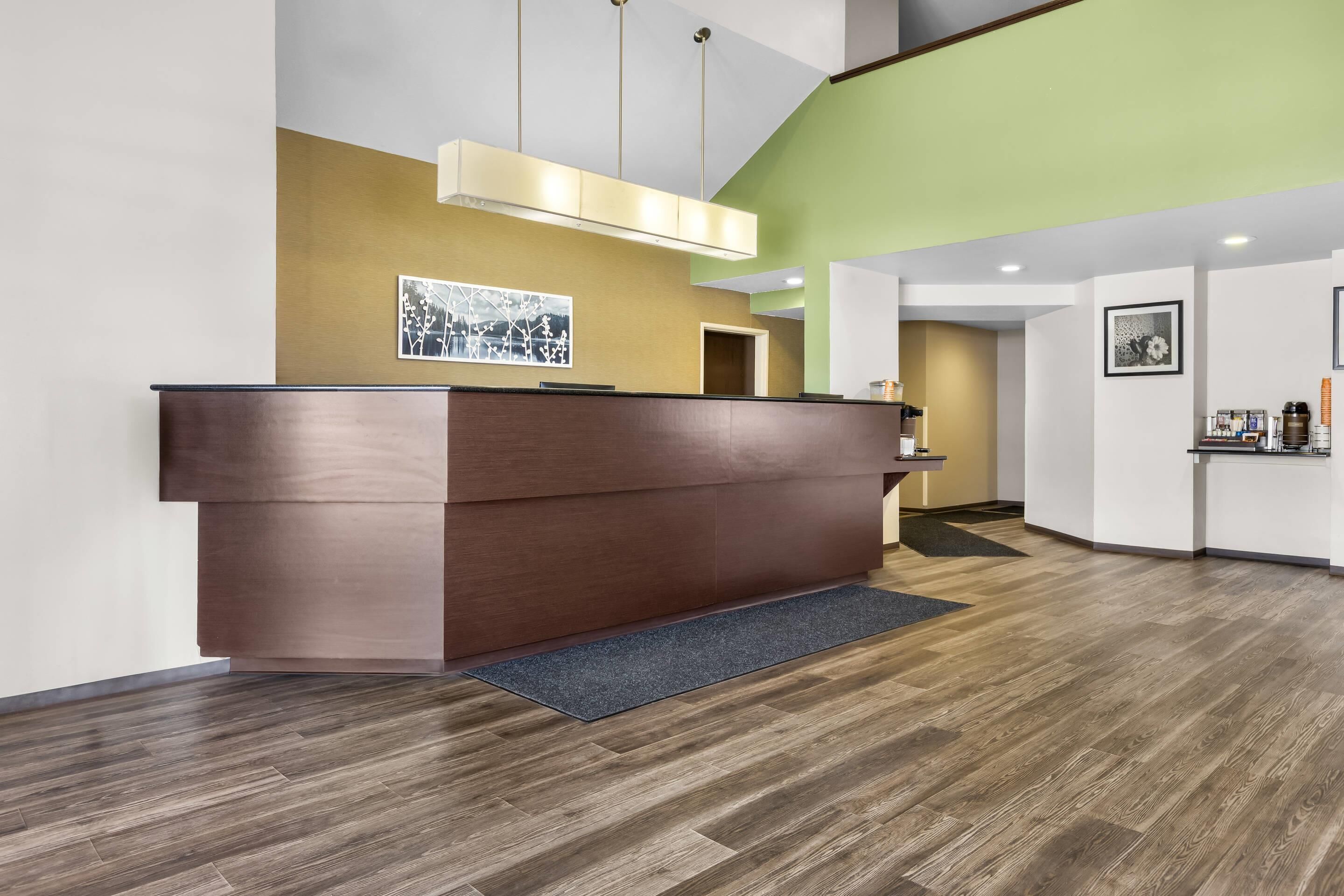 A reception desk with a modern design, a wooden floor, and a wall with a landscape painting.