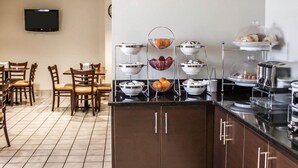 A hotel room with a kitchenette, a dining area with wooden chairs, and a flat-screen TV mounted on the wall. - Sleep Inn Nampa near Idaho Center (Nampa)