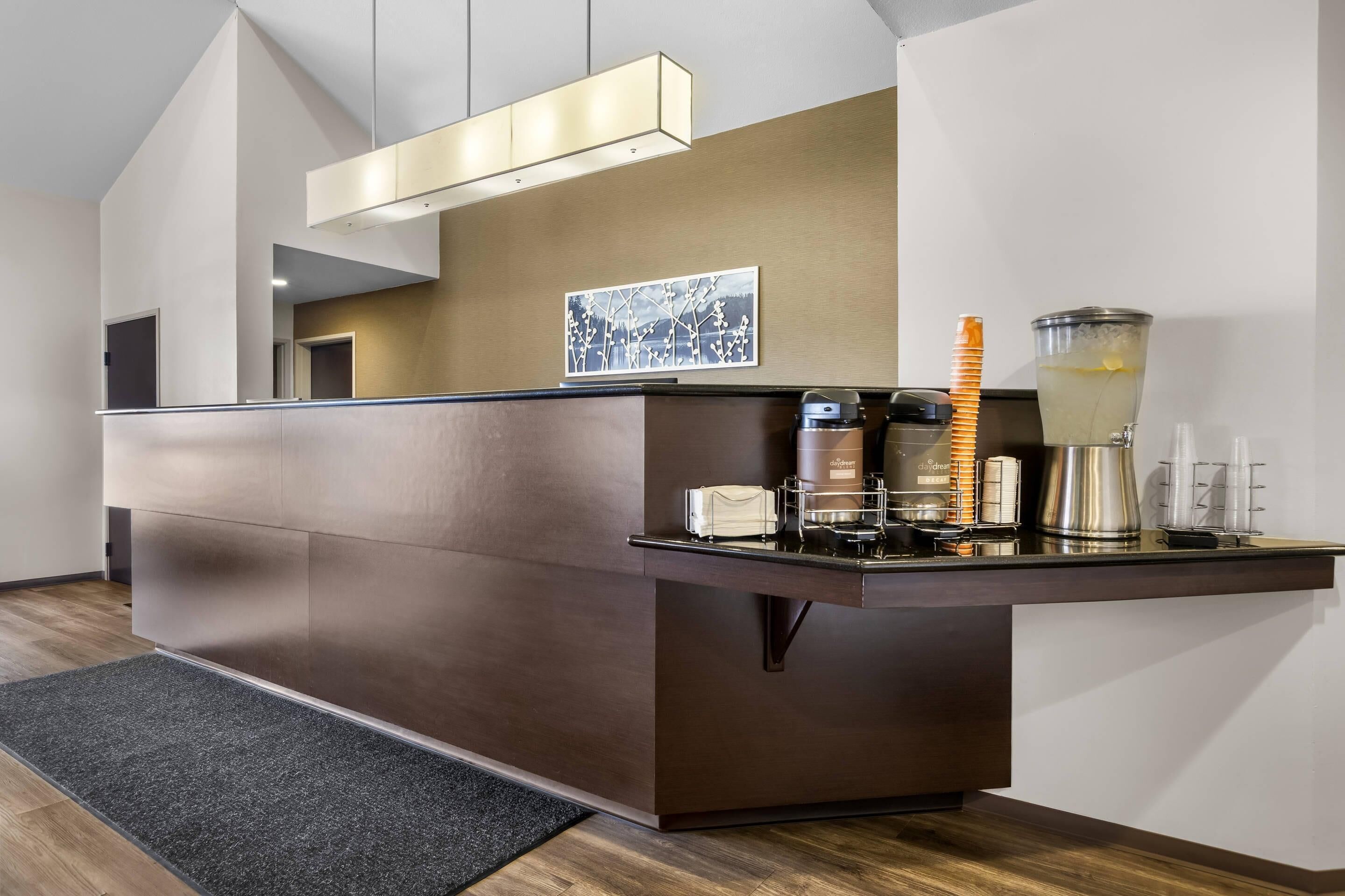 A modern reception desk with a coffee machine, a water dispenser, and a decorative item on the counter.