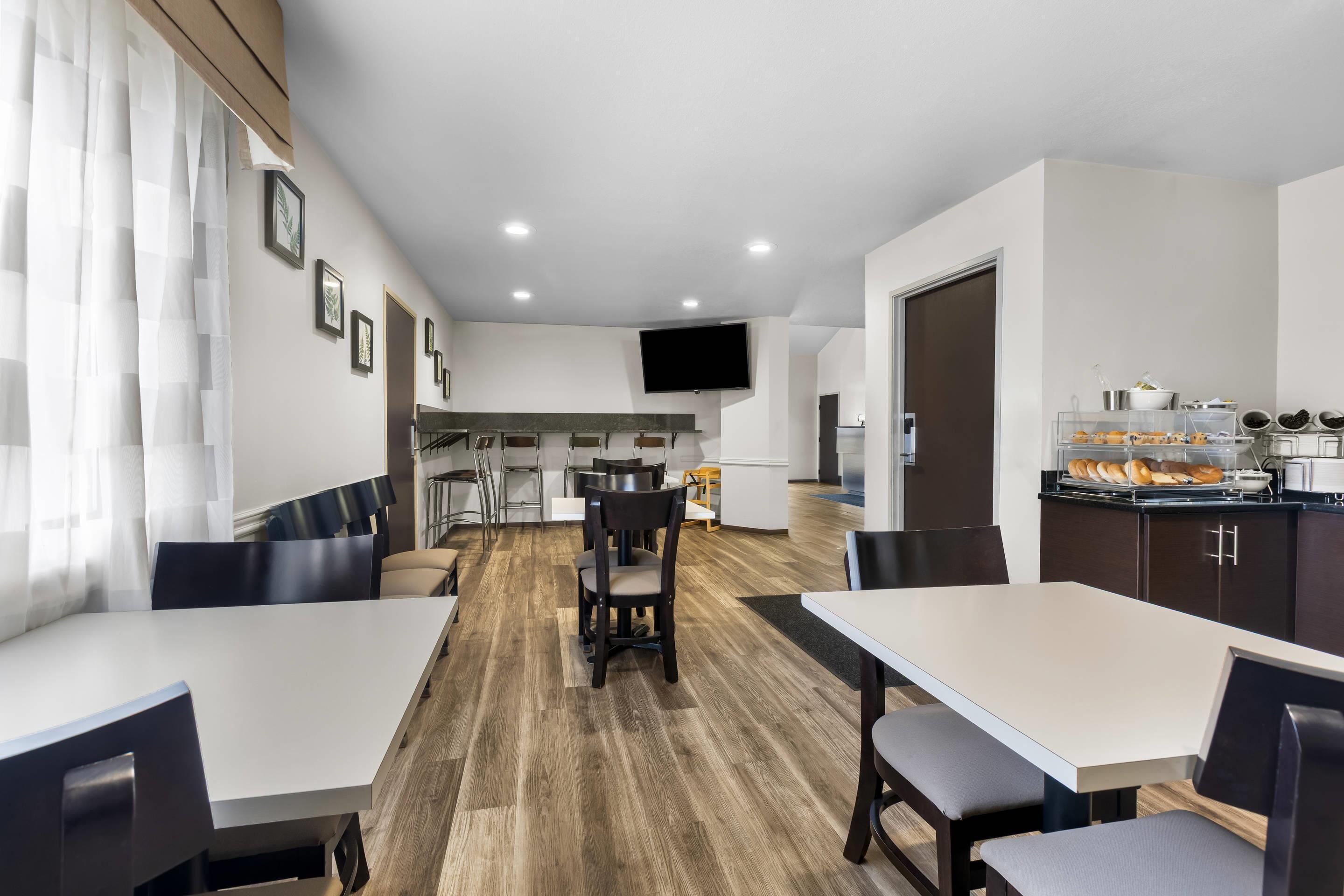 Una habitación de hotel moderna con comedor, cocina y televisor instalado en la pared.