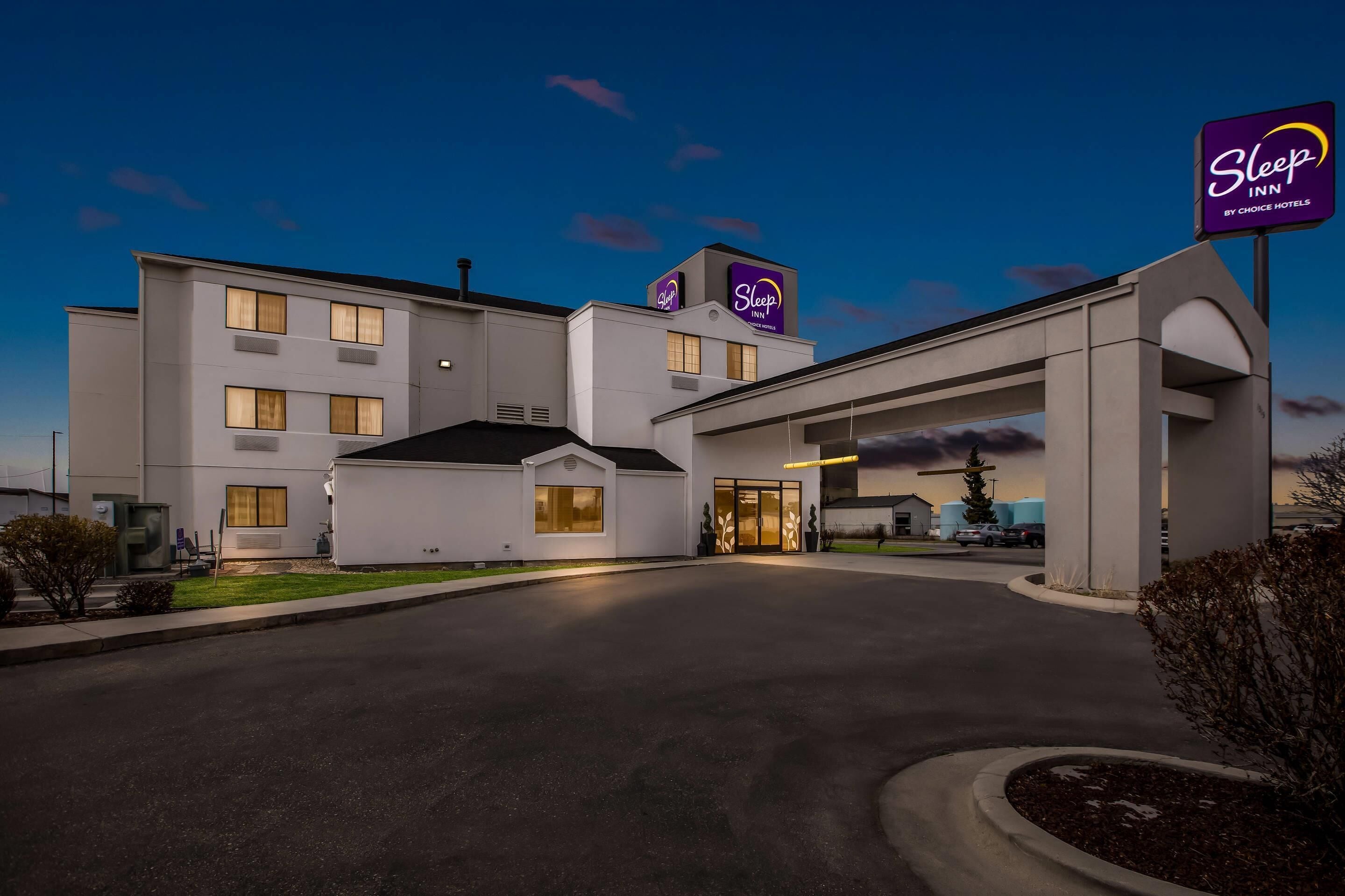 A Sleep Inn hotel with a modern design, featuring a large entrance and a parking area.