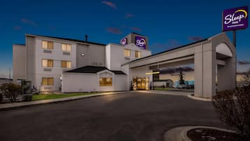 A Sleep Inn hotel with a modern design, featuring a large entrance and a parking area.