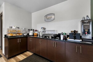 Una cocina moderna con zona de desayuno, que incluye una cafetera, plancha para gofres y diferentes alimentos.