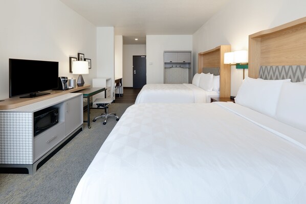 Une chambre d’hôtel équipée d’une télévision, d’un bureau, de deux lits et d’une kitchenette.