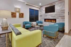 A modern living room with a fireplace, seating, and a large window.
