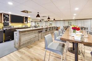 A modern hotel room with a bar area, dining space, and a view of the outdoors. - Holiday Inn Twin Falls by IHG (Twin Falls)