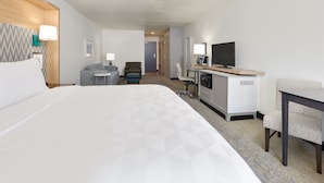 A hotel room with a large bed, a desk with a chair, a television, and a small seating area with a couch and armchair. - Holiday Inn Twin Falls by IHG (Twin Falls)