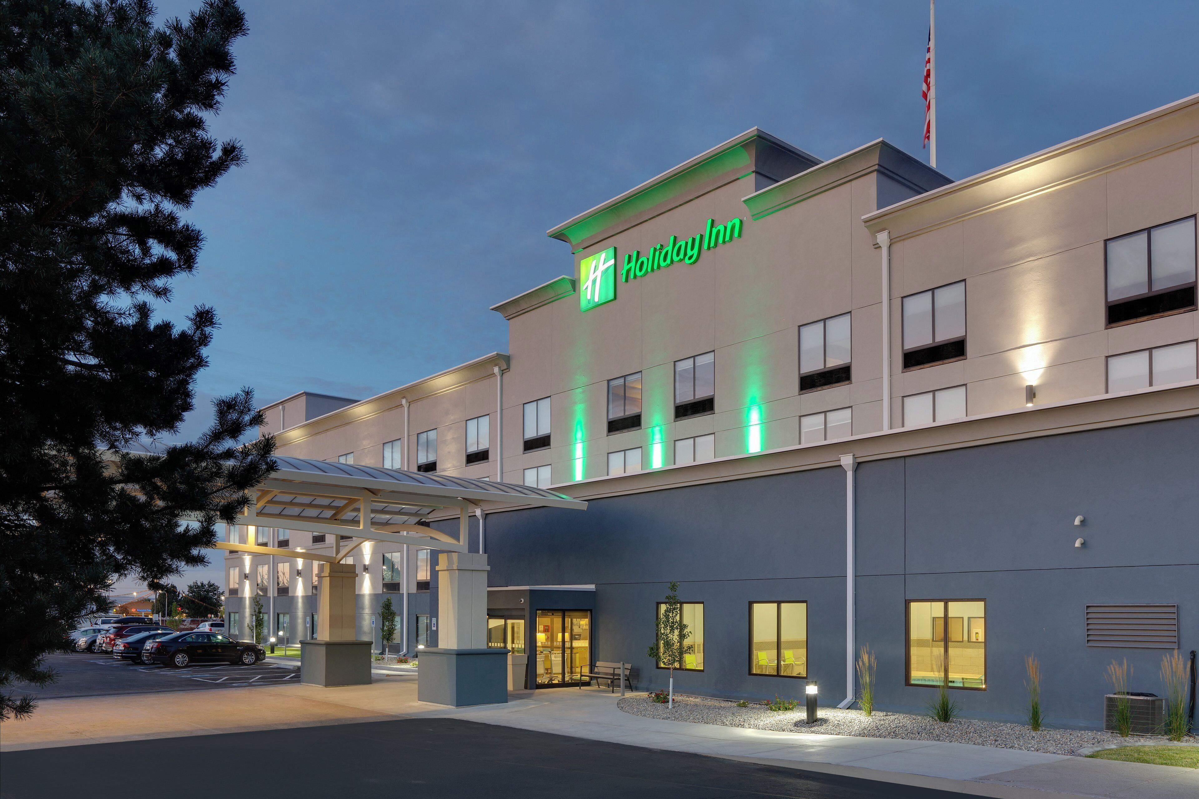 Un hotel Holiday Inn con facciata moderna, ingresso coperto e parcheggio con auto.