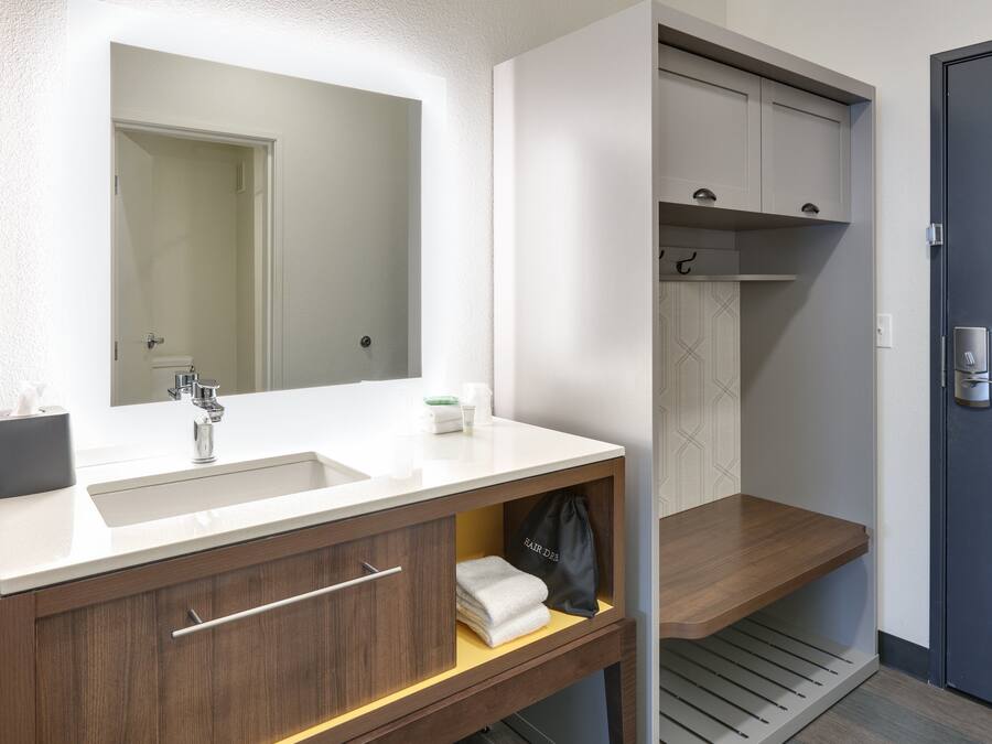 A modern bathroom with a white sink, wooden vanity, and a mirror above the sink.