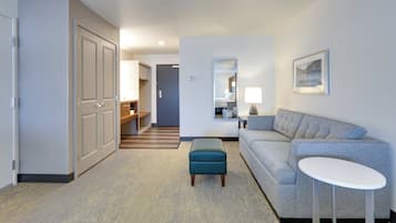 A hotel room with a large bed, a sofa, a small table, and a mirror.