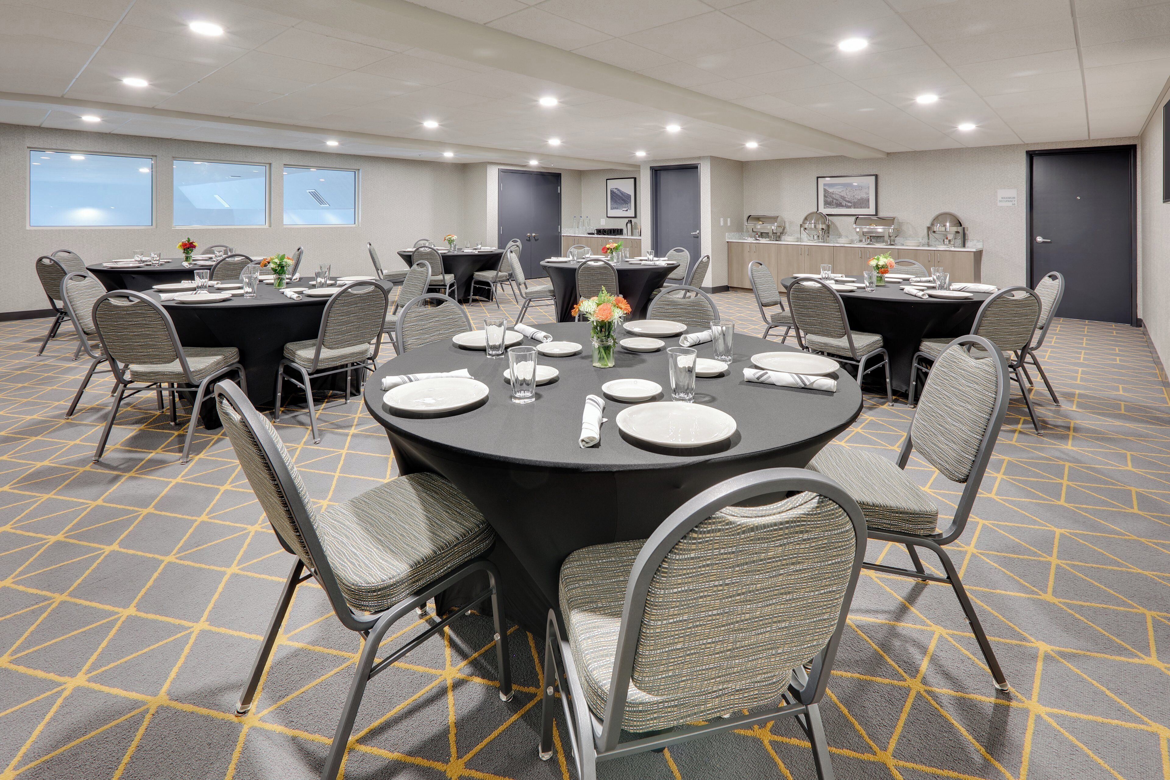 A conference room with round tables, chairs, and a kitchen area.