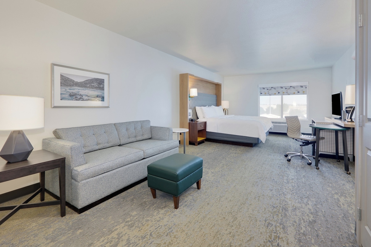 Une chambre d’hôtel comprenant un lit, un bureau avec un ordinateur, un canapé, une petite table et une chaise.