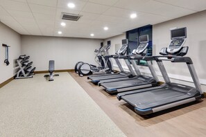 Un gimnasio con cintas de correr, máquinas de pesas y un saco de boxeo.