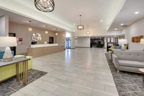 A hotel lobby with a reception desk, seating area, and a hallway leading to other rooms. - Holiday Inn Twin Falls by IHG (Twin Falls)