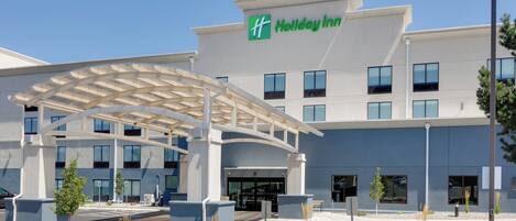 Un hotel Holiday Inn con entrada cubierta, múltiples ventanas y una bandera.