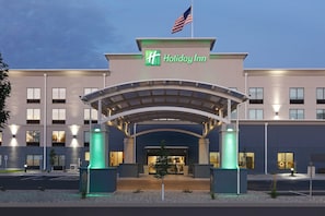 A Holiday Inn hotel entrance with a covered walkway, American flag, and illuminated pillars. - Holiday Inn Twin Falls by IHG (Twin Falls)