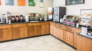 A self-service breakfast area with coffee machines, a clock, and labeled trash bins. - Quality Inn Lewiston (Lewiston)