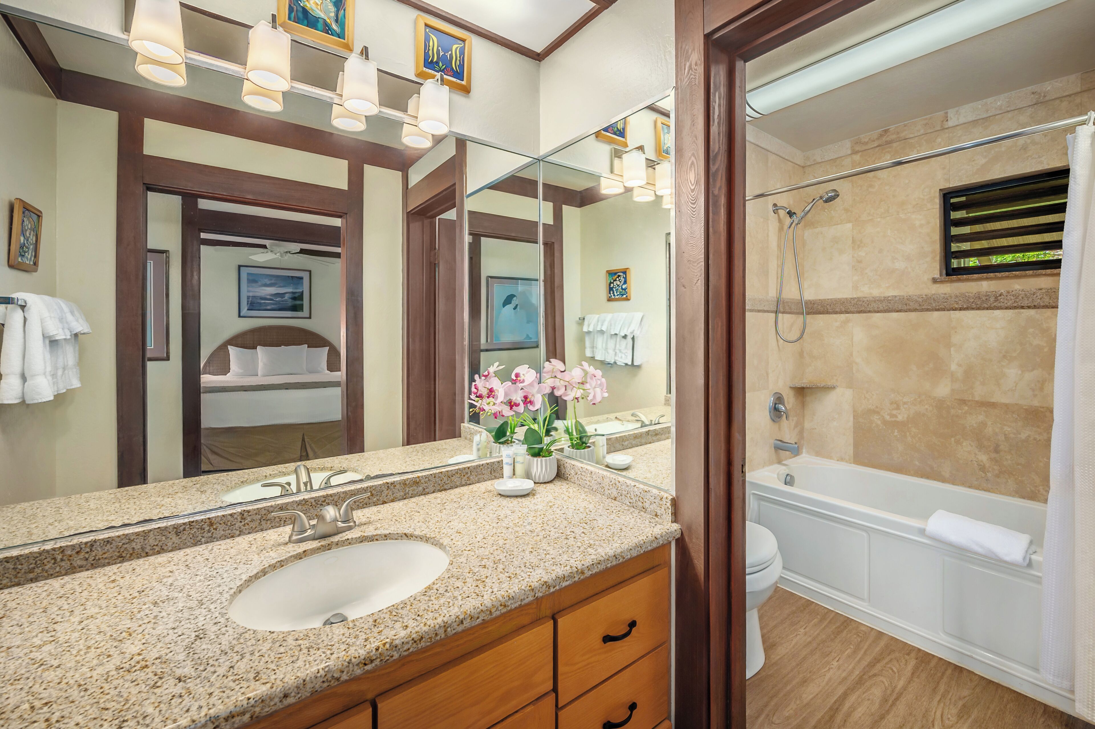 A bathroom with a large mirror, a sink, a toilet, and a bathtub.