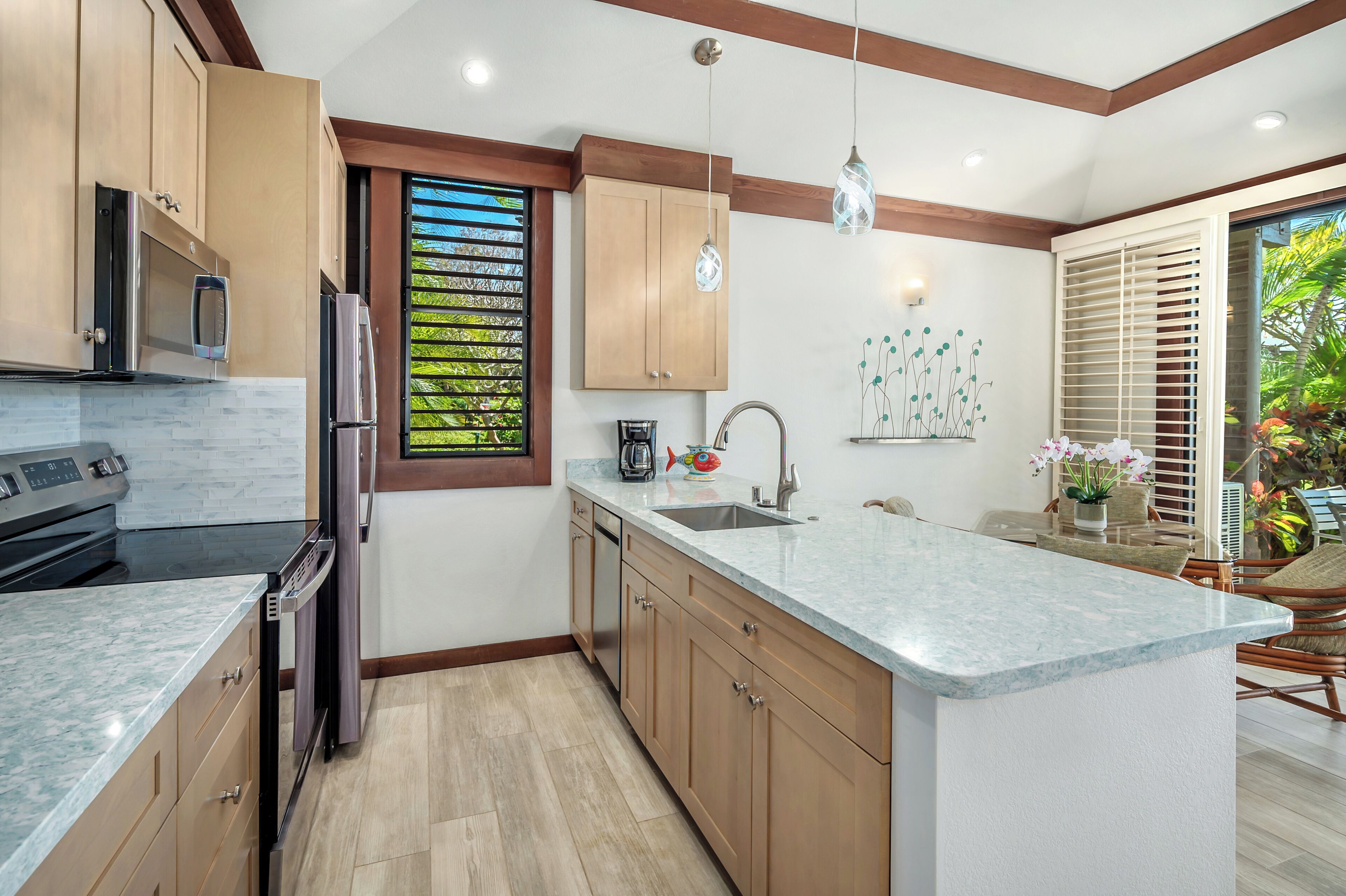 A modern kitchen with wooden cabinets, a marble countertop, and a built-in oven.