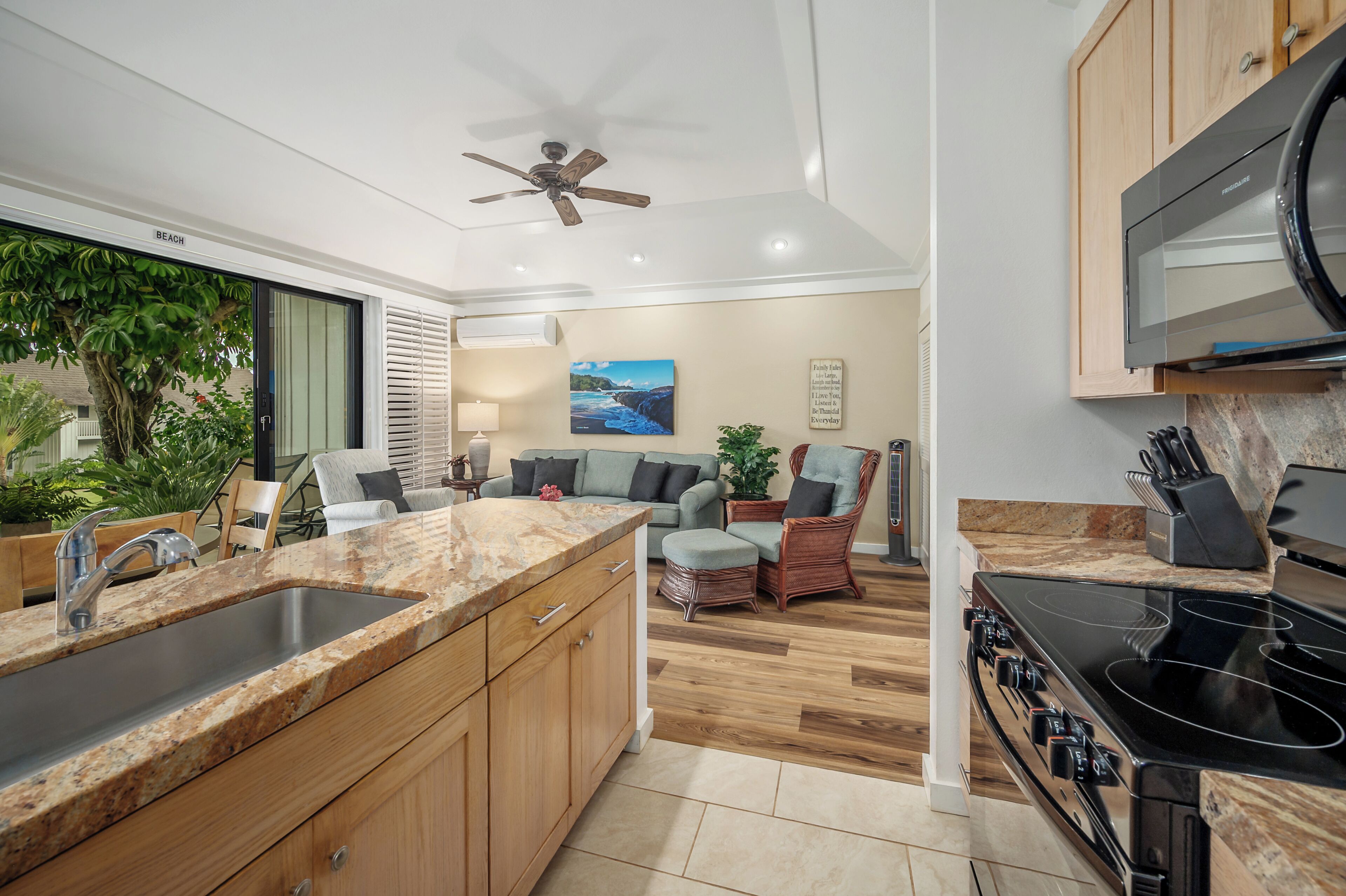 A modern kitchen with a built-in stove, a large sink, wooden cabinets, and a ceiling fan.