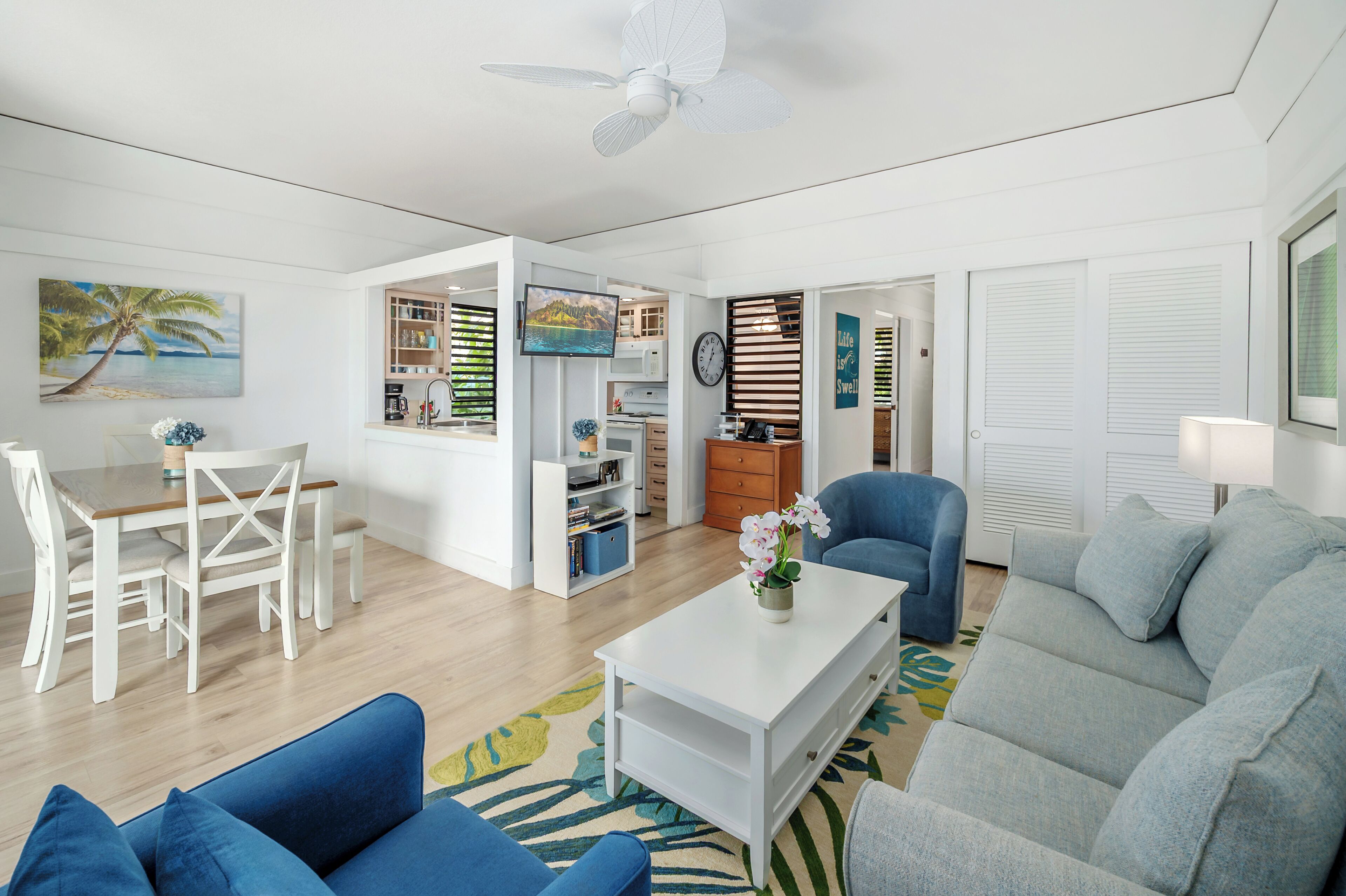A modern living room with a dining area, a kitchenette, and a bedroom.