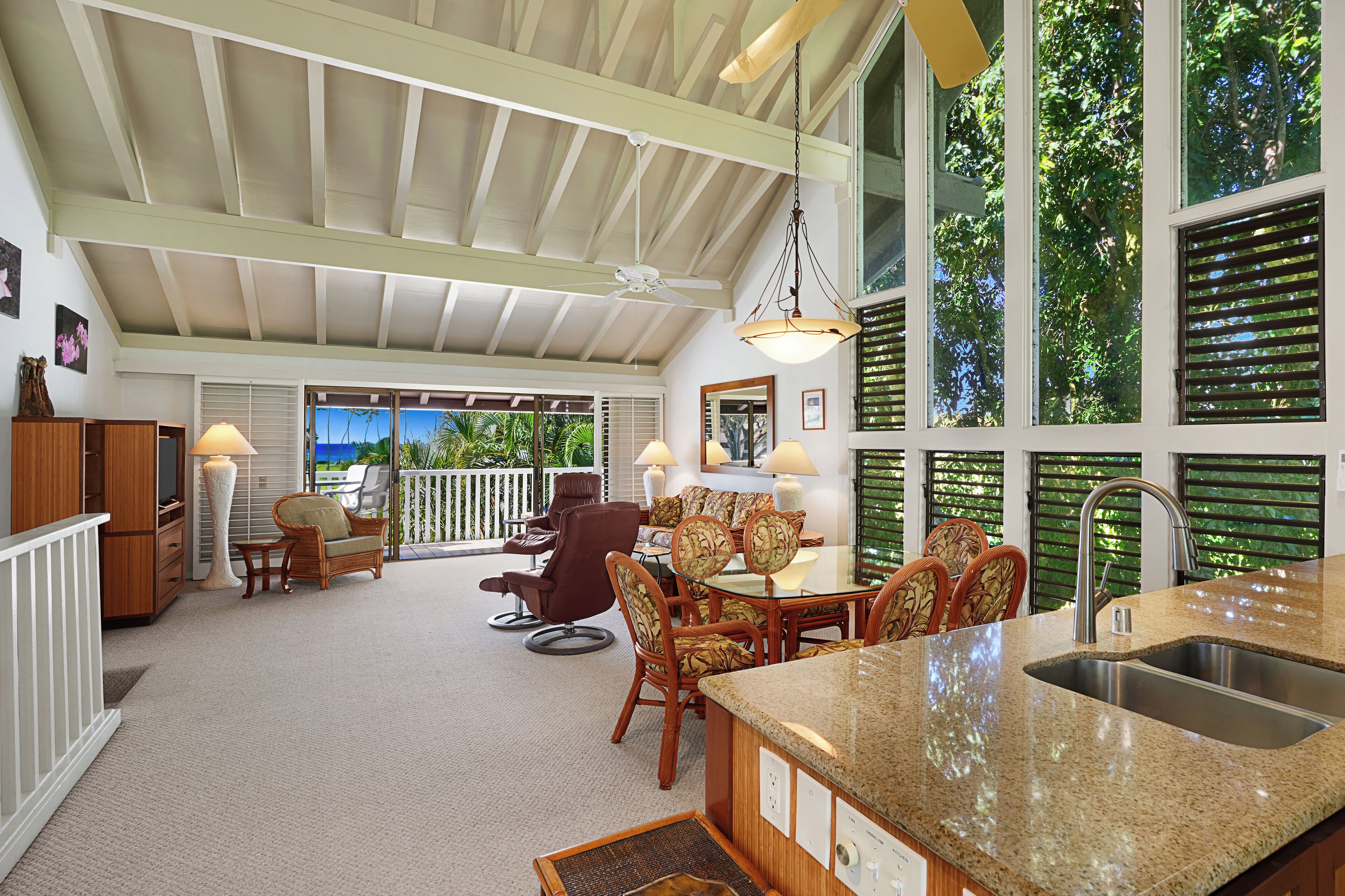 Una cocina amplia con una isla grande, un comedor con sillas de madera y vistas al exterior a través de grandes ventanales.