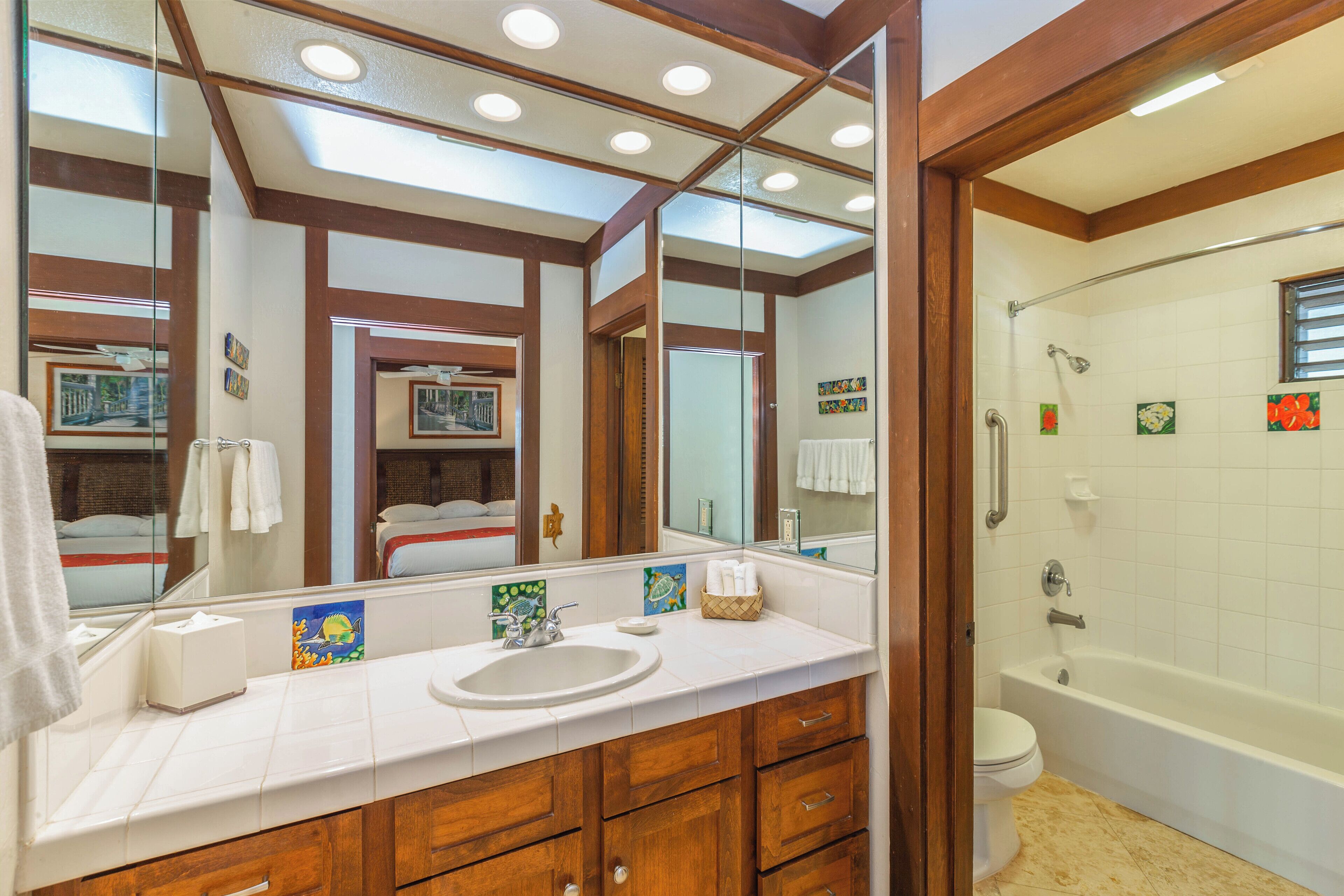 A bathroom with a large mirror, a sink, a toilet, and a bathtub.