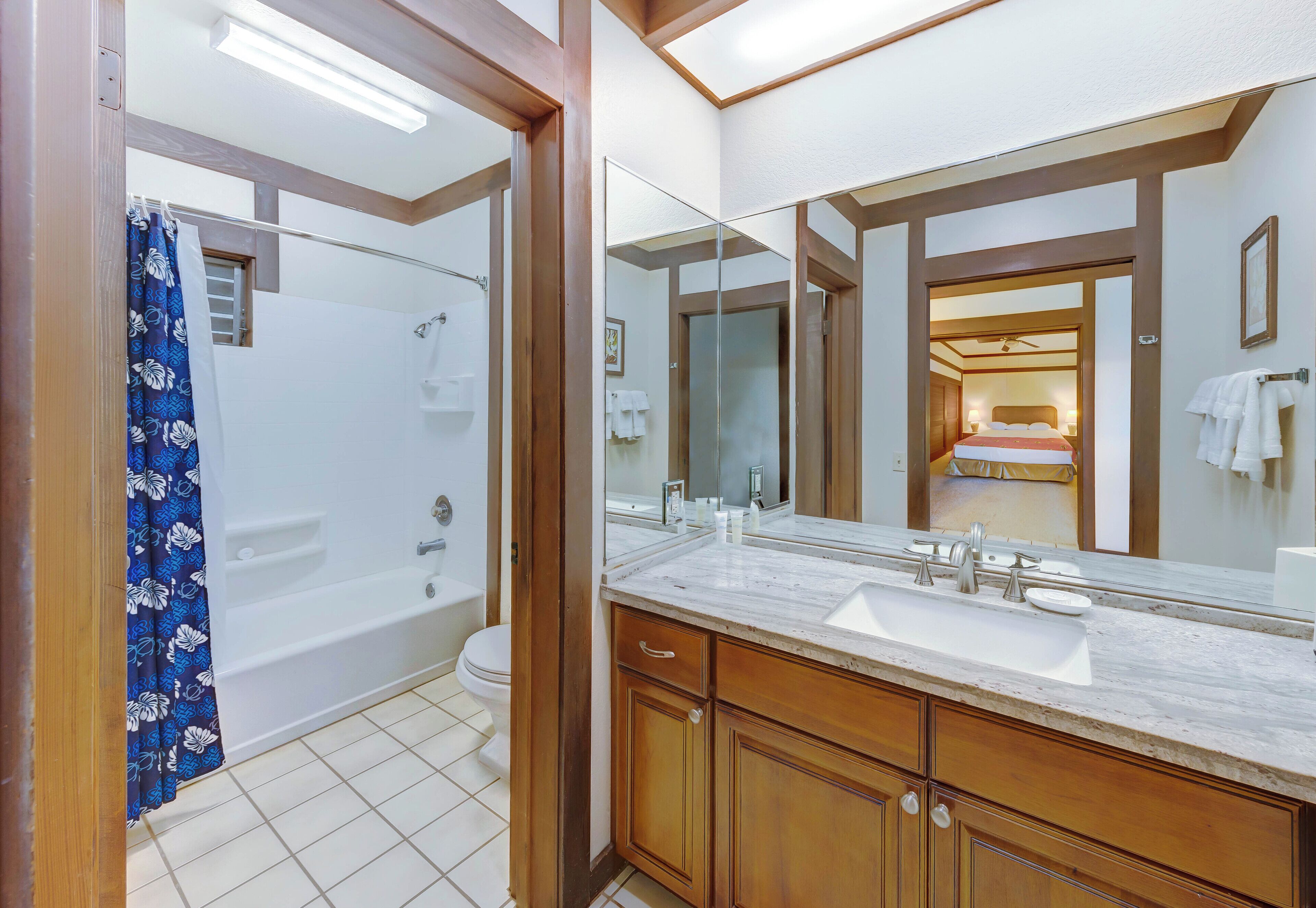A bathroom with a bathtub, a large mirror, and a sink.