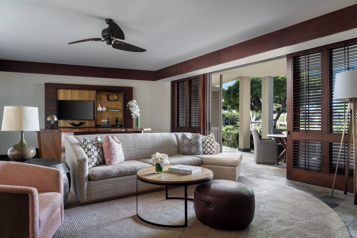 Una sala moderna con sofá, mesa de centro, reposapiés, televisor y comedor con mesa y sillas.