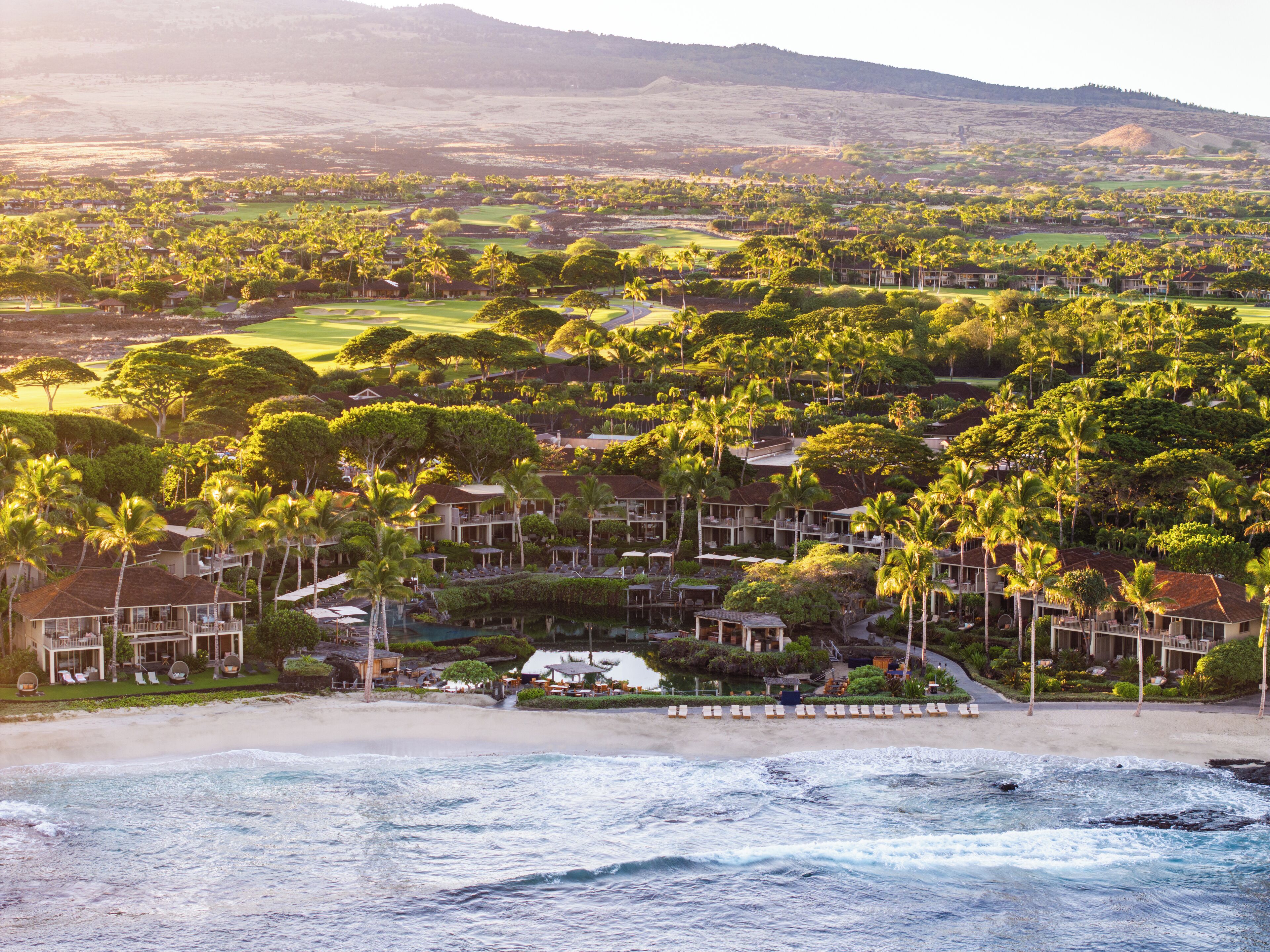 A resort with beachfront villas, a pool, and lush greenery.