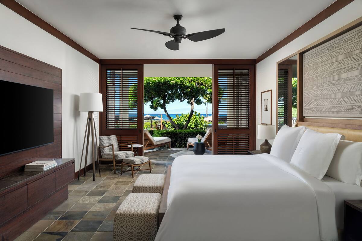 Un dormitorio con una cama grande, un televisor y vistas al exterior.