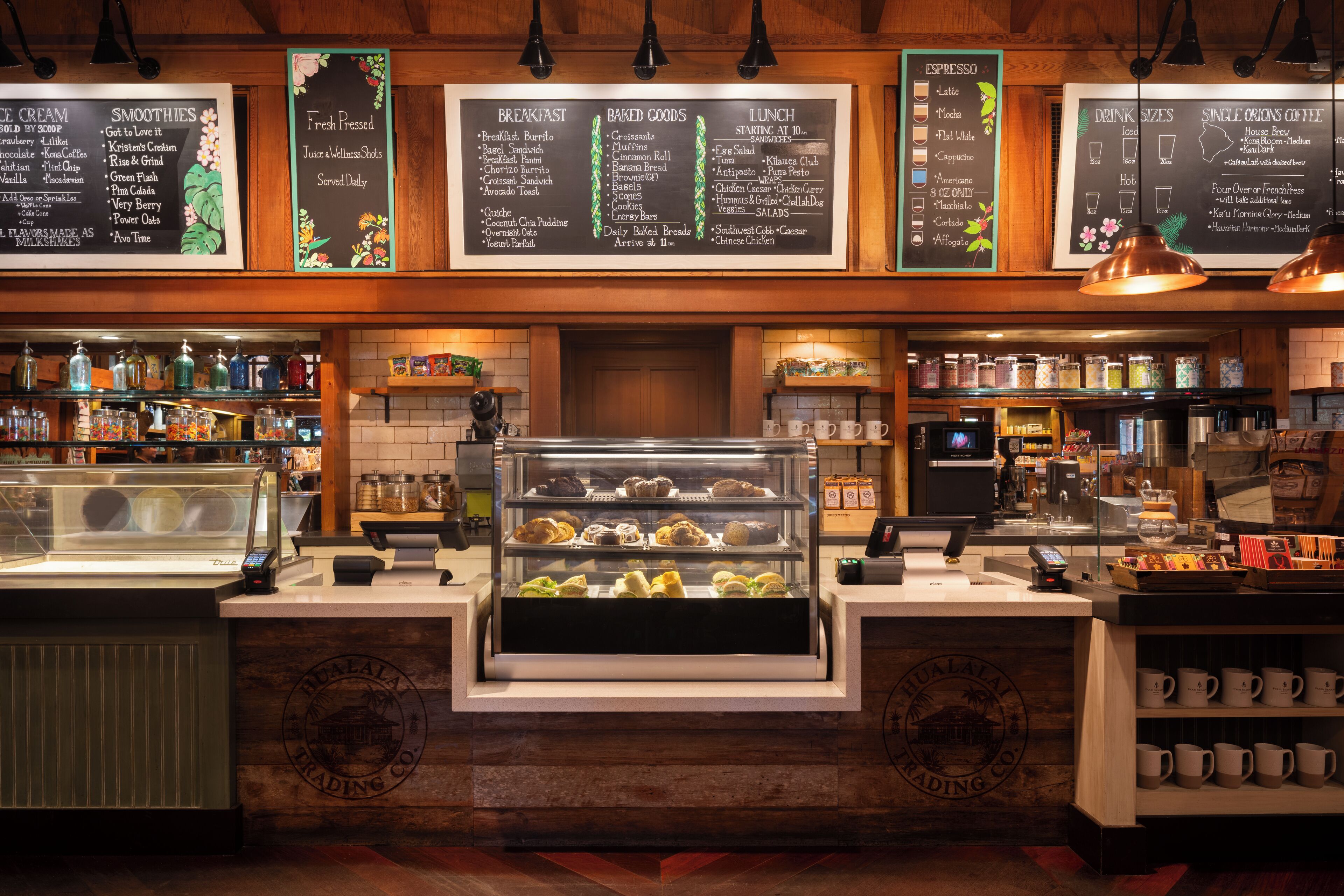 Un comptoir de boulangerie avec une vitrine remplie de pâtisseries et un tableau affichant le menu du petit-déjeuner, des produits de boulangerie et des plats pour le déjeuner.