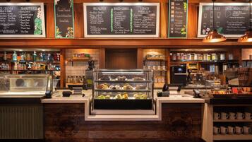 Un comptoir de boulangerie avec une vitrine remplie de pâtisseries et un tableau affichant le menu du petit-déjeuner, des produits de boulangerie et des plats pour le déjeuner.