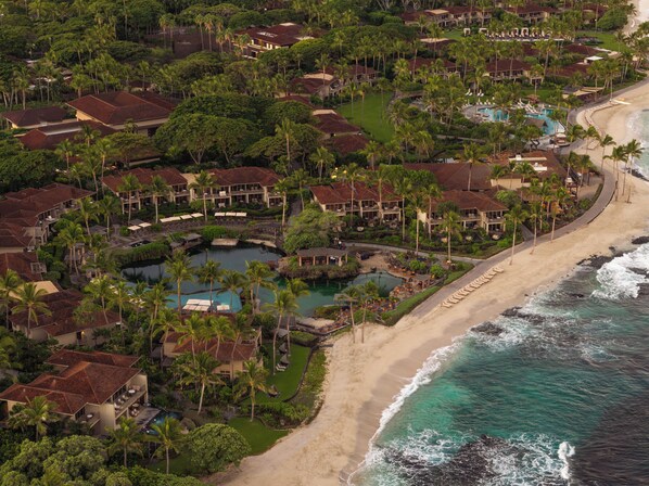 An aerial view of a resort with multiple buildings, a beach, and a pool area.