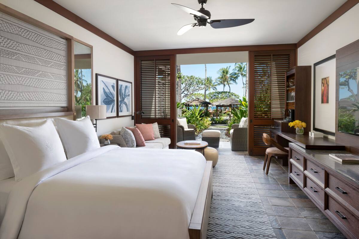 Un dormitorio con una cama grande, un escritorio y vistas al exterior.