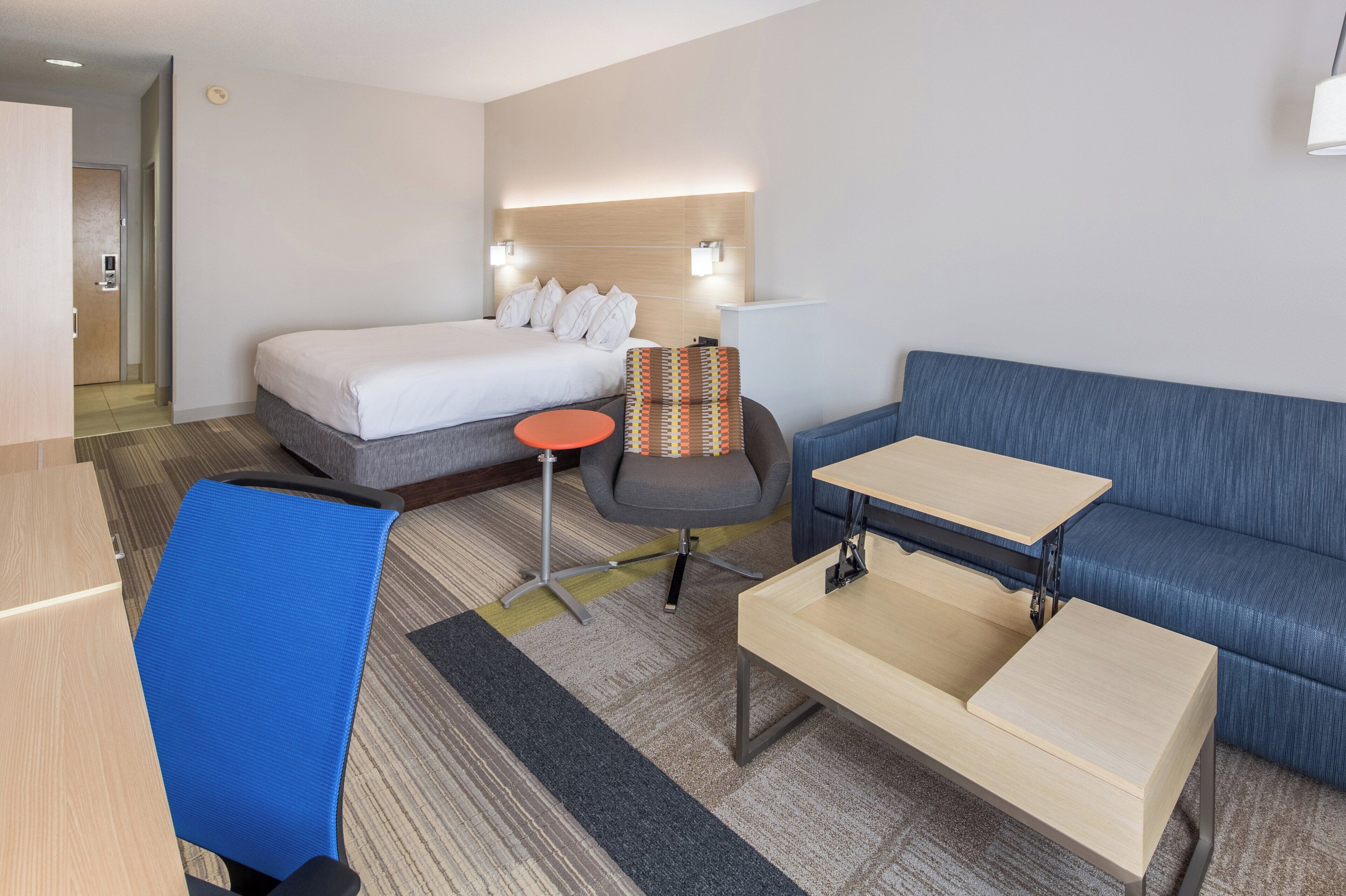 Une chambre d’hôtel comprenant un lit, un bureau, une chaise, un canapé et une petite table.