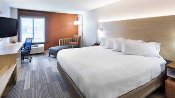 Habitación de hotel con una cama grande, un escritorio con silla, televisor y ventana.
