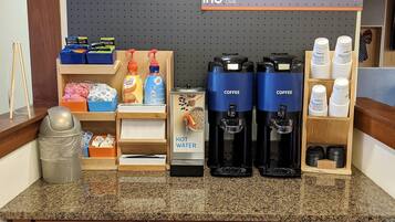 A coffee station with dispensers, a coffee machine, and a sign promoting a rewards club.