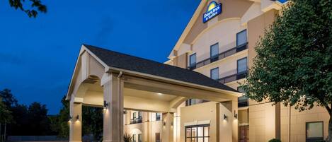 Un bâtiment de la chaîne Days Inn & Suites, doté d’une entrée abritée, de plusieurs balcons et surplombant un ciel dégagé au crépuscule.