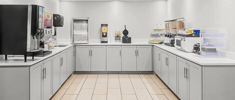 A modern kitchen with a coffee machine, a waffle maker, and a microwave.