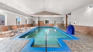 An indoor swimming pool with lounge chairs and a blue mat around the pool. - Days Inn & Suites by Wyndham Cedar Rapids (Cedar Rapids)