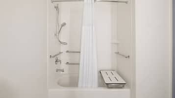 Ein modernes Badezimmer mit Badewanne, Duschkopf und Handlauf.