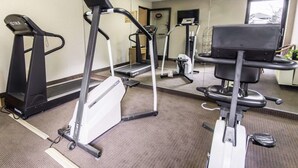 Un gimnasio con cintas de correr, bicicletas estáticas y una máquina de remo.