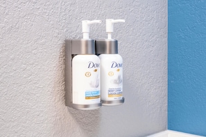 Two Dove hand wash bottles mounted on a wall. - Garner Hotel Louisville East by IHG (Louisville)