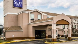 Un hotel Sleep Inn con un letrero llamativo, un acceso cubierto y un estacionamiento.