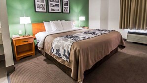 Habitación de hotel con una cama, dos lámparas de noche, una mesita de noche, un teléfono y una pared con tres cuadros enmarcados.
