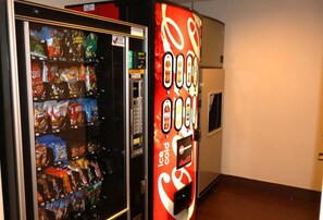 A vending machine with a Coca-Cola logo and a refrigerator stocked with snacks.