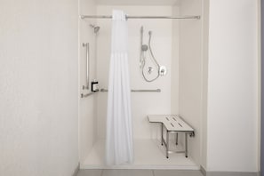 Ein modernes Duschbad mit Glastür, Duschbrause, Wandarmatur und einer kleinen Sitzbank.