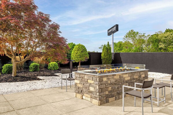 An outdoor patio area with a stone fire feature, seating, and a sign indicating a courtyard.