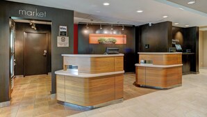A reception area with two wooden reception desks, a wall-mounted plant, and a sign indicating a boarding pass area.